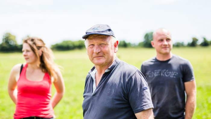 un agriculteur seniror et un couple d'agriculteurs juniors dans un champ