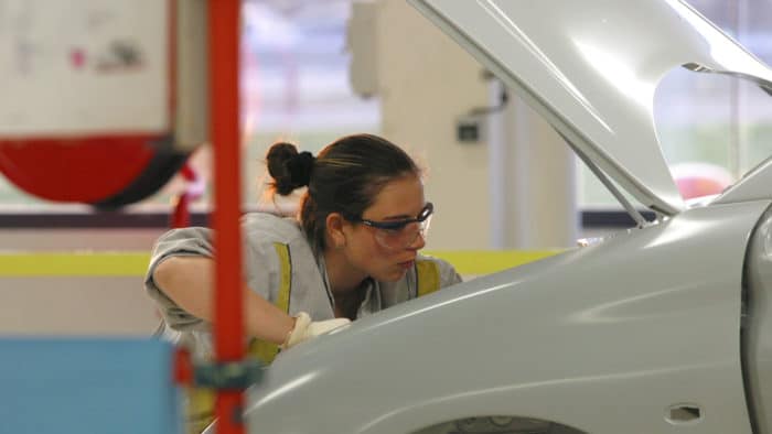 gros plan sur une jeune fille travaillant sur la carrosserie d'une voiture