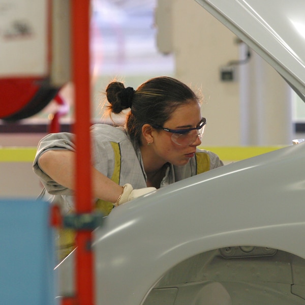 gros plan sur une jeune fille travaillant sur la carrosserie d'une voiture