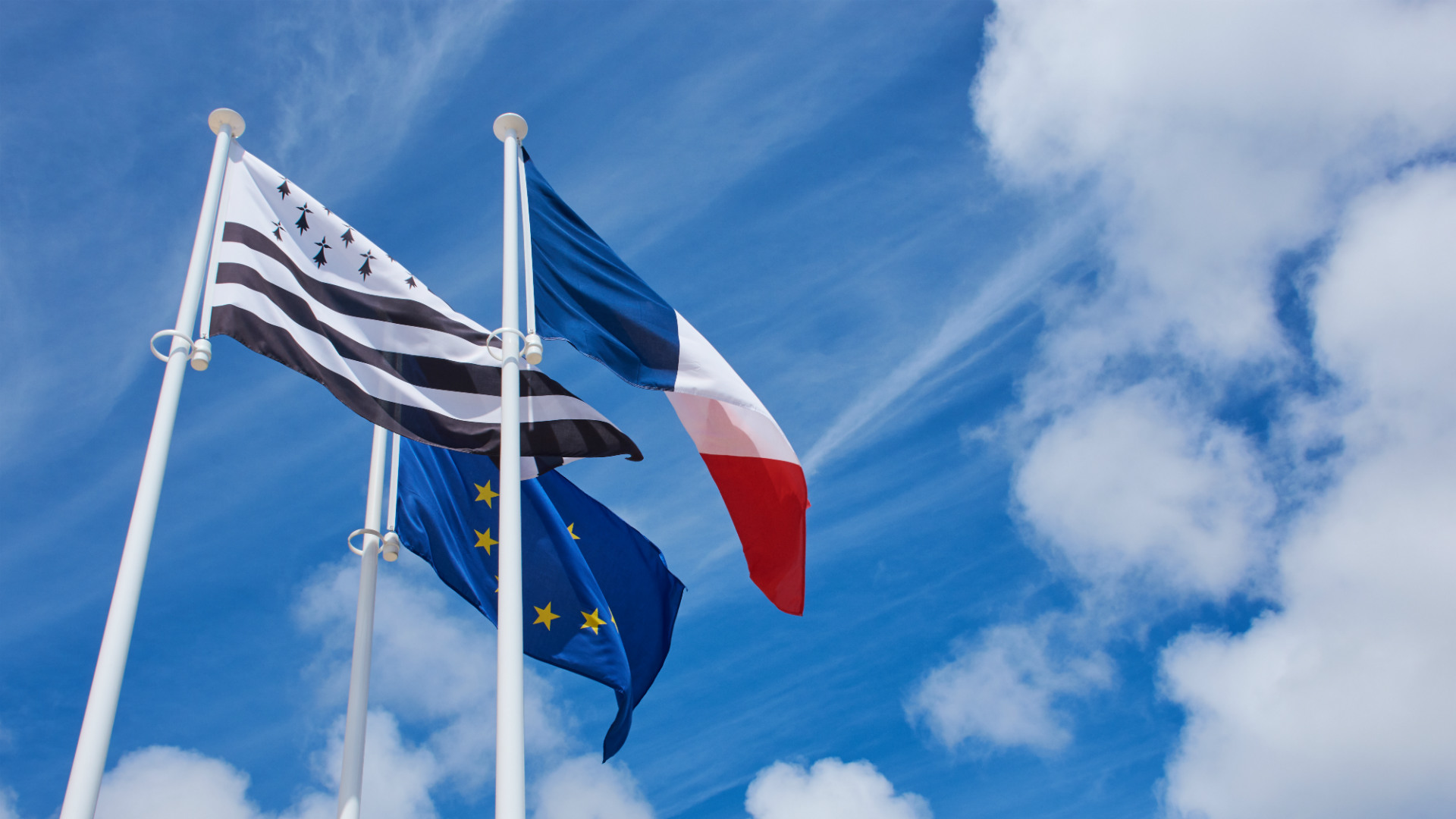 Drapeaux français, européen et breton flottant dans le ciel