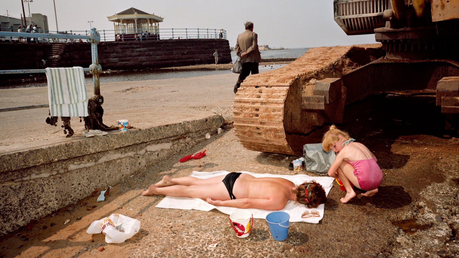 Gros plan sur deux enfants anglais jouant comme à la plage à l'ombre d'un tank abandonné dans une fiche industrielle près de la plage