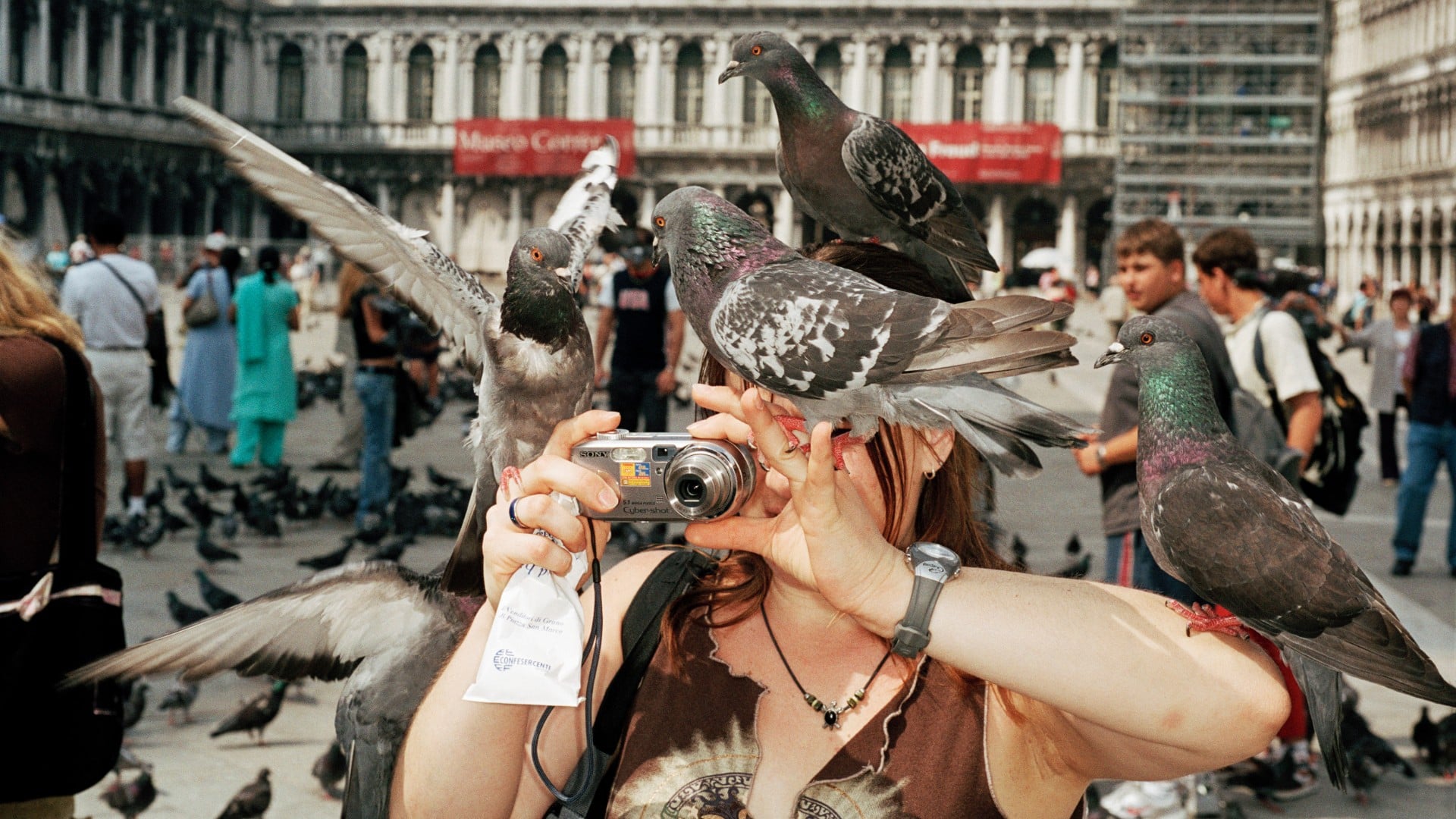 gros plan sur une femme se prenant en selfie couverte de pigeons sur la place Saint-Marc de Venise