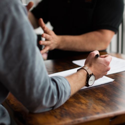 Vue sur une table et les mains de 2 hommes en réunion de travail