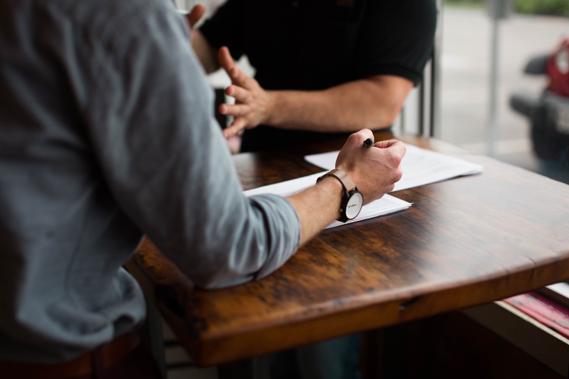 Vue sur une table et les mains de 2 hommes en réunion de travail