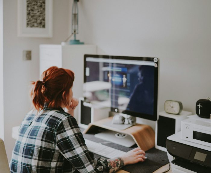 Une femme assise à son bureau entrian de travailler sur son ordinateur