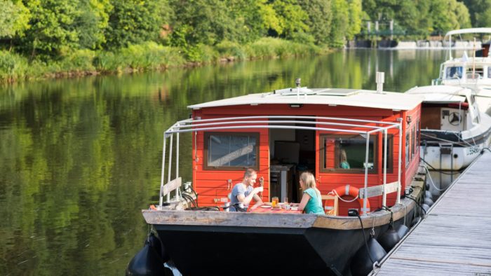 Touristes prenant leur petit déjeuner à bord d'une péniche à quai, sur le Blavet à Vue sur le Blavet, à Bieuzy-les-Eaux (56)