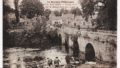 Photo ancienne en noir et blanc - Vue animée du Blavet et du pont de pierre. Au premier plan, des femmes lavent leur linge au bord de la rivière. 1923