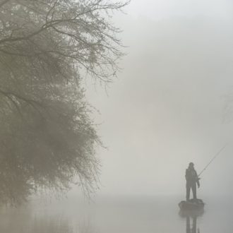 Pêcheur sur le canal à bord d'une barque dans la brume (voir l'image en plus grand)