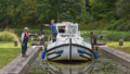 Péniche passant l'écluse avec l'aide d'un éclusier, sur le site des 11 écluses à Hédé-Bazouges (35) sur le canal d'Ille-et-Rance