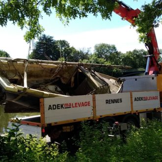 Une épave de voilier chargée sur un camion s'apprête à rejoindre une usine de recyclage