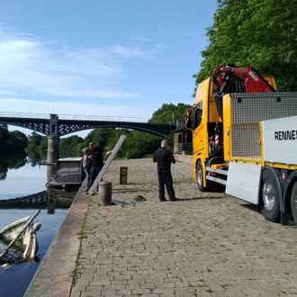 Les agents de la Région s'apprêtent à extraire un petit voilier coulé dans la Vilaine, près du quai sur la commune de Langon