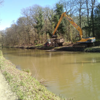 Un tractopelle dépose la vase extraite du canal dans un camion avant son transport (voir l'image en plus grand)