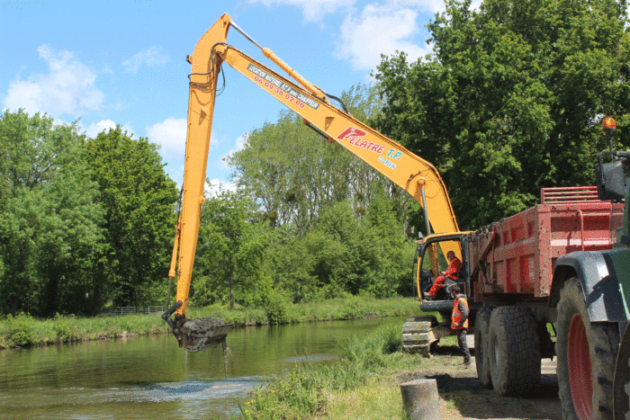 Un tractopelle extrait de la vase du canal