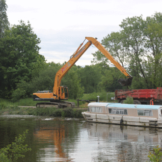 Un tractopelle dépose la vase extraite du canal dans un camion avant son transport (voir l'image en plus grand)