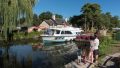 famille avec enfants regardant un bateau passer devant une maison éclusière abriant un petit restaurant