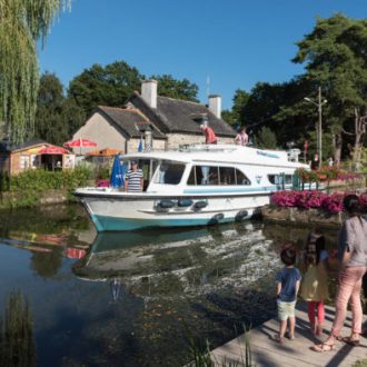 famille avec enfants regardant un bateau passer devant une maison éclusière abriant un petit restaurant (voir l'image en plus grand)