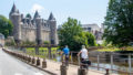 couple à vélo le long d'un canal passant à proximité d'un château