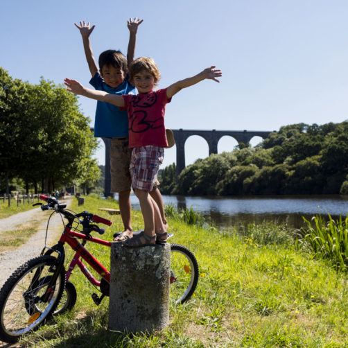 enfants avec leur vélo au pied d'un pont le long du canal