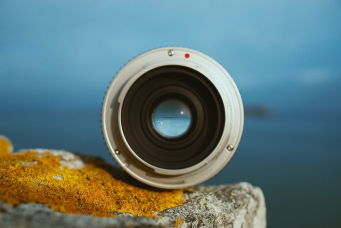 Un objectif d'appareil photo posé sur un rocher et tourné vers l'horizon
